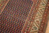 Antique Malayer rug's navy field with repeating rust boteh, ivory serrated border, and light foundation striation.