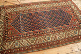 Antique Malayer rug corner detail: navy boteh field, rust chestnut serrated border, ivory floral spandrel.