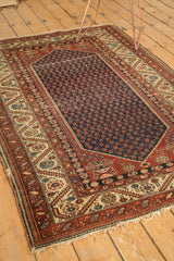Corner detail of the antique Malayer rug, showing ivory spandrel, rust chestnut serrated border, and worn fringe.