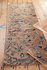 Corner detail of antique Kerman runner, showcasing blue floral palmettes and hand-bound pink selvage.