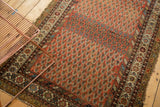 Persian Hamadan rug: madder red boteh field with abrash, ornate border, and edge tatter.