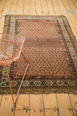 Bottom edge detail of Hamadan antique rug, madder red boteh field, varied borders, tattered fringe.