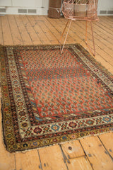 Antique Hamadan rug corner, detailed border with diverse colors, madder red field, and tattered edge.