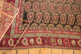 Antique Karabagh rug corner with wine red borders and traditional boteh patterns.