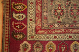 Antique Karabagh carpet corner featuring crimson borders, ivory vine motifs, and germinating plant botehs.