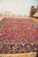 Vintage Heriz carpet close-up: fringe, navy border, and worn red, gold, blue patterns.