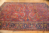 Vintage traditional Heriz carpet with allover serrated leaf design, cherry red and navy, showing wear.