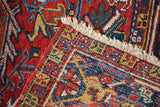 Detail of Vintage Heriz carpet: secured ivory fringe, navy and gold border, and red pile wear.