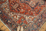 Vintage Heriz rug: intricate cherry red, navy blue, and ivory geometric patterns with serrated forms.