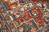 Heriz carpet pile texture showing cherry red, navy blue, and cream geometric motifs.