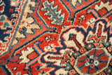 Textured hand-knotted Heriz rug pile with serrated geometric patterns, red, navy, and cream.