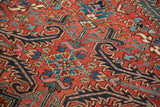Heriz carpet detail: serrated leaves, floral pinwheels, brick red, navy, teal, and subtle wear.