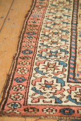 Detail of hand-knotted Kurdish runner's madder red border and geometric field on camel ground.