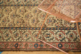 Vintage Kurdish runner's intricate border patterns, short pile, and tattered dark brown end.
