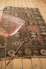 Hand-knotted Avar Caucasian rug showcasing worn geometric patterns in madder red and blue with tattered fringes.