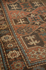 Geometric Avar motifs in dusty madder, dark brown, and teal on the antique Caucasian rug.