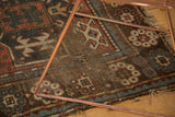 Aged geometric patterns, threadbare texture, and tattered fringe of an antique Caucasian rug.