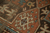 Geometric crab motifs in madder, brown, and ivory on the rug's worn pile.