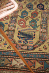 Antique Caucasian prayer rug: dusty gold field, madder red botehs, arrowed border, visible hole.