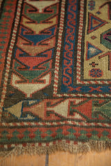 Antique Caucasian rug corner, showcasing geometric arrowed border, pawn motif, and tattered fringe.