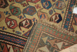 Folded antique Caucasian rug: dusty gold field, repeating boteh, tattered ends, foundation.