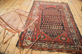 Antique Hamadan rug corner: navy boteh field, red floral spandrel, vine border, tattered edges.