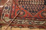 Antique Hamadan rug's madder root red field and elegant ivory meandering vine border, with end tatter.