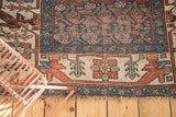 Antique Kurdish Bijar rug's worn indigo pile, tattered fringe, and geometric ivory border.