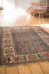 Antique Kurdish Bijar rug corner, geometric border, worn indigo field, tattered fringe.