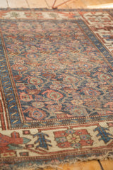 Antique Kurdish Bijar rug's worn indigo field, visible foundation, and tattered fringe.