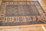 Antique Kurdish Bijar rug with storied wear, indigo boteh pattern, and tattered ends.