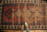 Textured field of an antique Caucasian rug with geometric motifs and exposed foundation.