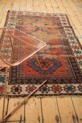 Hook and latch border motif, aged texture, and visible foundation of an antique Caucasian rug.