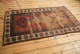 Antique Caucasian rug detail: worn field texture, visible foundation, and geometric hook motif border.