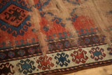 Antique Caucasian rug showing textured wear, foundation recess, and a geometric border.