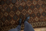 Detail of antique Turkmen Yomud carpet with geometric panels and distinctive border in bronze, teal, ivory.