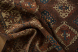 Hand-knotted geometric panel design on a folded antique Yomud carpet in bronze, teal, ivory.