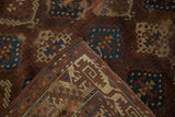 Folded corner of antique Yomud rug showing geometric bronze, teal, ivory patterns and border.