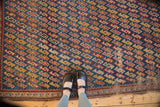Antique Caucasian rug's serpentine lattice pattern in indigo, red, and yellow with tattered lower edge.