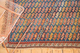 Antique Caucasian rug detail showing indigo blue geometric serpent pattern, madder red border, worn fringe.