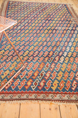 Angled view of antique Caucasian rug, allover geometric serpent motif in blue, red, yellow.