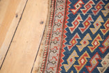 Tattered side edge and geometric serpent motif on an antique indigo Caucasian rug.