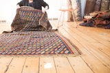 Antique Caucasian rug display, showcasing geometric serpent lattice in indigo, red, and saffron.