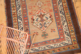 Antique Serab rug runner showing repeating medallions, starburst motifs, and an aubergine stripe border.
