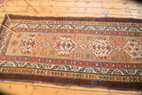 Repeating geometric medallions and starburst motifs on natural camel field with rare aubergine border.