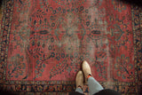 Intricate floral vinery design on a dusty raspberry Lilihan rug, showing wear.