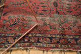 Dusty raspberry Lilihan rug's intricate floral vinery, navy border, visible wear, and tattered edges.