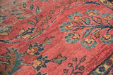 Intricate vinery and stemmed blossoms in dusty raspberry red, sky blue, and navy, with visible worn pile.