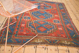 Antique Caucasian rug's corner with intricate geometric border and lightly tattered fringe.