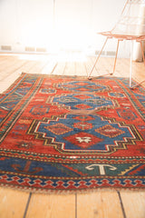 Antique Caucasian rug's geometric lower border with cherry red, sky blue, and white 'T' motif.